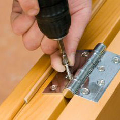 Person adjusting a door hinge.